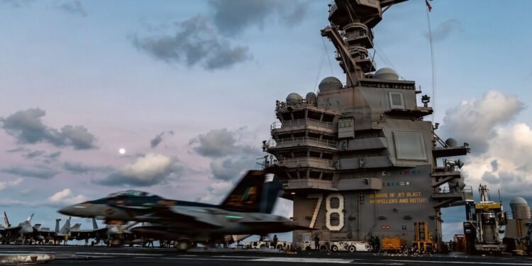 Ein F-18 Jet startet trotz des Feuer auf der USS Gerald Ford vom Flugdeck.